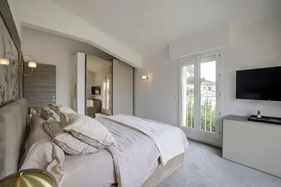 a white bedroom with a bed and a flat screen tv at Villa Julia First in Vallauris