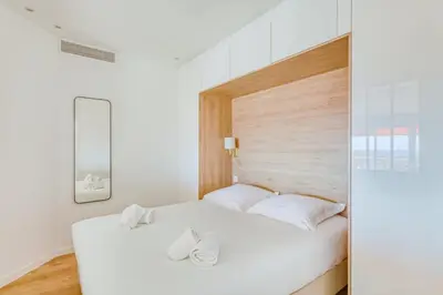 a bedroom with a white bed with white pillows at LE VOILIER avec terrasse panoramique vue mer et port, proche du Palais, Croisette et plages in Cannes