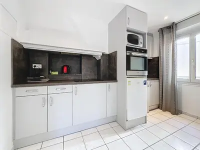 a kitchen with white cabinets and a microwave at Central 1 bedroom Riouffe 206 2 mins from Palais in Cannes