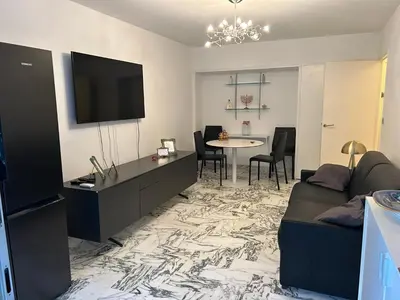 a living room with a couch and a tv and a table at Appartement T2 bord de mer in Cannes
