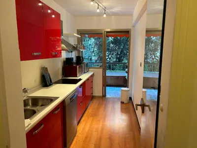 a kitchen with red cabinets and a large window at Appartement T2 bord de mer in Cannes
