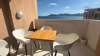 a table and chairs on a balcony with a view of the ocean at Appartement 4 personnes sea view pool in Cannes