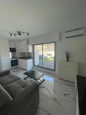 a living room with a couch and a kitchen at Cannes Appartement Terrasse Parking privé in Cannes