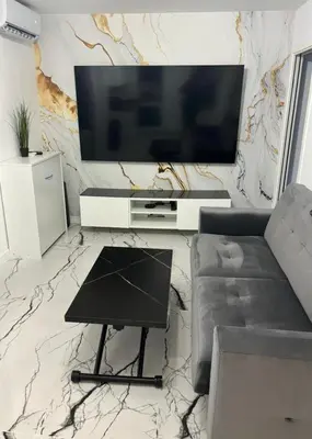 a living room with a flat screen tv on a marble wall at Cannes Appartement Terrasse Parking privé in Cannes