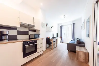 a kitchen with white cabinets and a living room at Cannes 1-Br Apartment in the Carré d’Or in Cannes