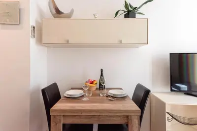 a small dining room table with chairs and a television at Cannes 1-Br Apartment in the Carré d’Or in Cannes
