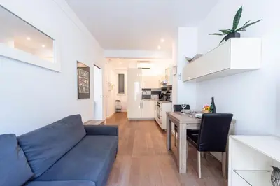 a living room with a blue couch and a kitchen at Cannes 1-Br Apartment in the Carré d’Or in Cannes