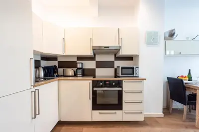 a small kitchen with white cabinets and a table at Cannes 1-Br Apartment in the Carré d’Or in Cannes