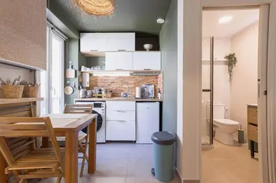 a kitchen with white cabinets and a table in a room at Kaméa - Palais & plage, clim, vieux Suquet, port in Cannes