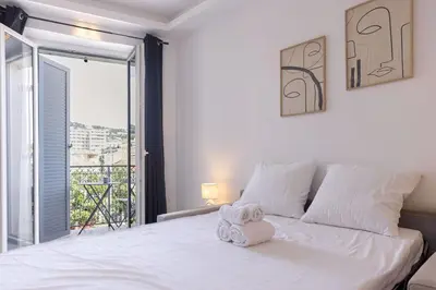 a bedroom with a white bed with a large window at Studio Jules - Bd de Lorraine in Cannes
