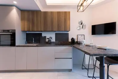 a kitchen with white cabinets and a black counter top at Studio Charlie - Bd de Lorraine in Cannes