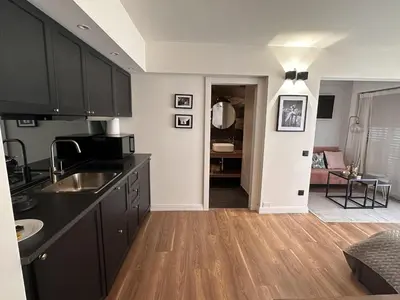 a kitchen with black cabinets and a living room at Modern studio in the hearth of Cannes just a few steps from the Croisette beach front and shops - 2242 in Cannes