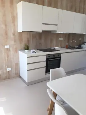 a white kitchen with white cabinets and a table at 3 ROOMS - DOWNTOWN CANNES - 2 MIN FROM PALAIS Festivals in Cannes