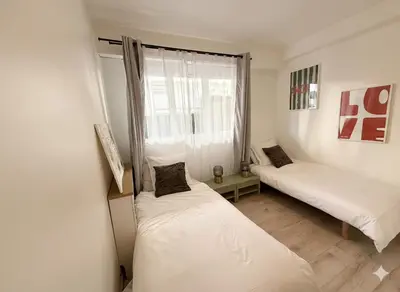 two beds in a room with a window at Appartement terrasse Croisette in Cannes