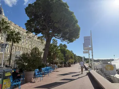 a man walking down a sidewalk next to a tree at Appartement terrasse Croisette in Cannes