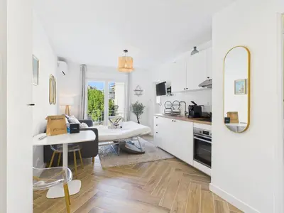 a kitchen with white cabinets and a table and a desk at LA BELLE PLAGE près de la plage du Midi, Palais des Festivals et centre-ville in Cannes