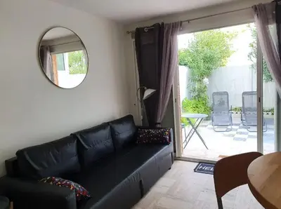 a living room with a black leather couch and a mirror at studio Pointe Croisette avec terrasse in Cannes