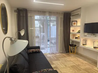 a living room with a black couch and a television at studio Pointe Croisette avec terrasse in Cannes