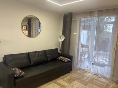 a living room with a black couch and a mirror at studio Pointe Croisette avec terrasse in Cannes