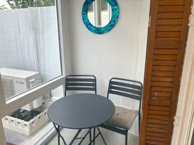 a table and chairs on a balcony with a mirror at studio Pointe Croisette avec terrasse in Cannes