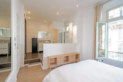 a bedroom with a white bed and a table at Bel appartement avec balcon centre ville in Cannes