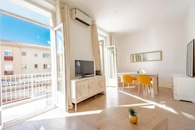 a living room with a television and a table with chairs at Bel appartement avec balcon centre ville in Cannes