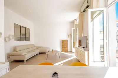 a white living room with a couch and a tv at Bel appartement avec balcon centre ville in Cannes