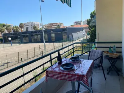 a table on a balcony with a view of a tennis court at Charming apartment in the centre of Cannes in Cannes