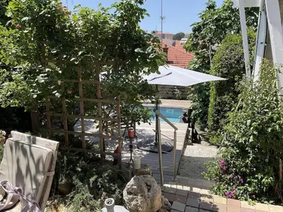 a garden with a white umbrella and a pool at Villa 12MN Walk from le palais in Cannes