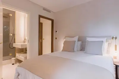 a white bedroom with a large bed and a bathroom at La Réale Croisette in Cannes
