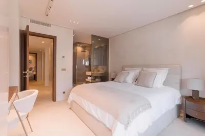 a white bedroom with a large bed and a chair at La Réale Croisette in Cannes
