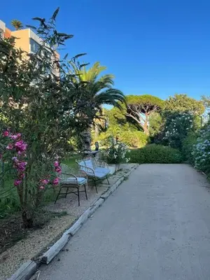 a walkway with two benches and flowers in a park at Cannes in Cannes