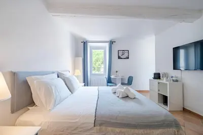 a white bedroom with a large bed with white pillows at Confortable appartement - Cannes centre le Suquet in Cannes