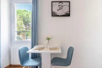 a white table with blue chairs and a window at Confortable appartement - Cannes centre le Suquet in Cannes