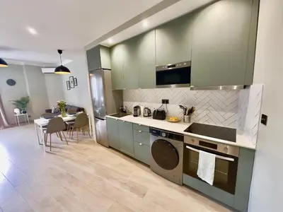 a kitchen with green cabinets and a table with chairs at Cosy Home Cannes - Croisette in Cannes