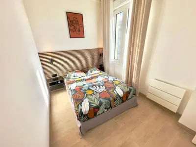 a bedroom with a bed with a colorful comforter and a window at Cosy Home Cannes - Croisette in Cannes