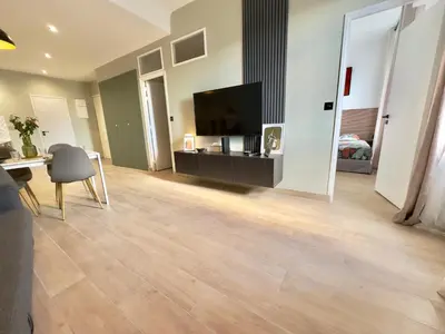 a living room with a flat screen tv and a wooden floor at Cosy Home Cannes - Croisette in Cannes