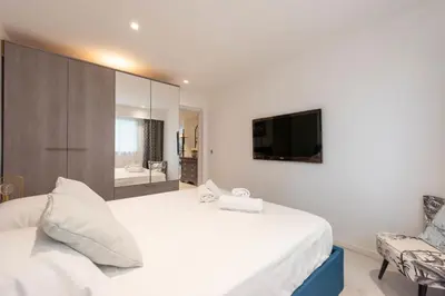a bedroom with a large white bed and a television at RARE! 2-Br with Pools Beach Access Private Parking in Cannes