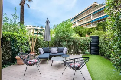 a patio with a couch and chairs and an umbrella at RARE! 2-Br with Pools Beach Access Private Parking in Cannes