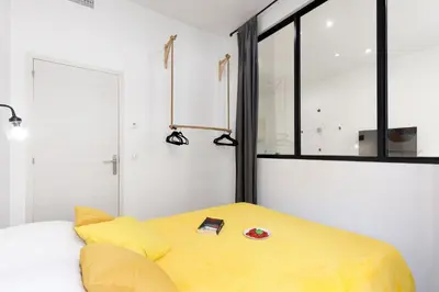 a bedroom with a yellow bed and a window at L'Elégant YourHostHelper in Cannes