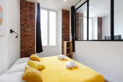 a bedroom with a yellow bed with towels on it at L'Elégant YourHostHelper in Cannes