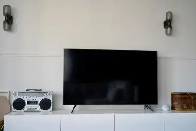 a flat screen tv sitting on top of a white cabinet at T2 Appartement 55m2 Terrasse 20m2 - à 15min à pied du Centre Ville - Wifi - Air conditioning in Cannes