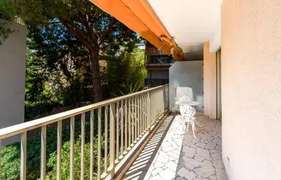 a balcony with a table and an umbrella at Studio Fenelon terrasse et Parking Cannes in Cannes