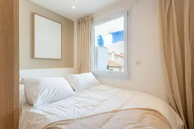 a white bed in a room with a window at Sublime 3 pièces entièrement rénové dans le centre de Cannes in Cannes