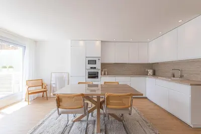 a kitchen with white cabinets and a table and chairs at Sublime 3 pièces entièrement rénové dans le centre de Cannes in Cannes