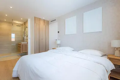 a bedroom with a large white bed and a bathroom at Sublime 3 pièces entièrement rénové dans le centre de Cannes in Cannes