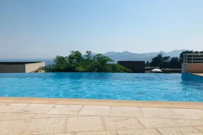 a large blue swimming pool with mountains in the background at Le Seaview - Calm - Pool - Farniente - Sea view in Cannes