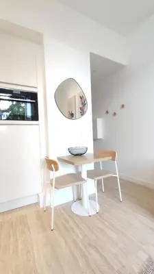 a white room with a table and chairs and a mirror at Studio rénové, vue dégagée et arborée, 700m plage in Cannes