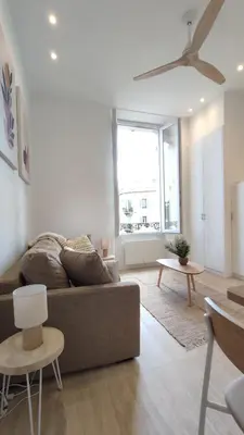 a living room with a couch and a large window at Studio rénové, vue dégagée et arborée, 700m plage in Cannes