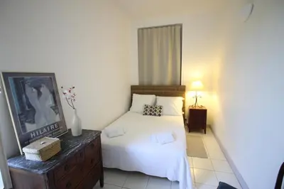 a bedroom with a white bed and a dresser with a picture at Villa Cottage Reine, RC Jardin in Cannes